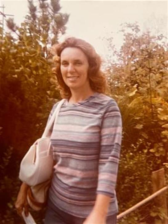 A woman walks on a forest path, smiling and enjoying the peaceful surroundings of nature.