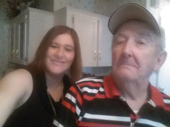 A woman and an elderly man smile together in a cozy kitchen, enjoying family time.