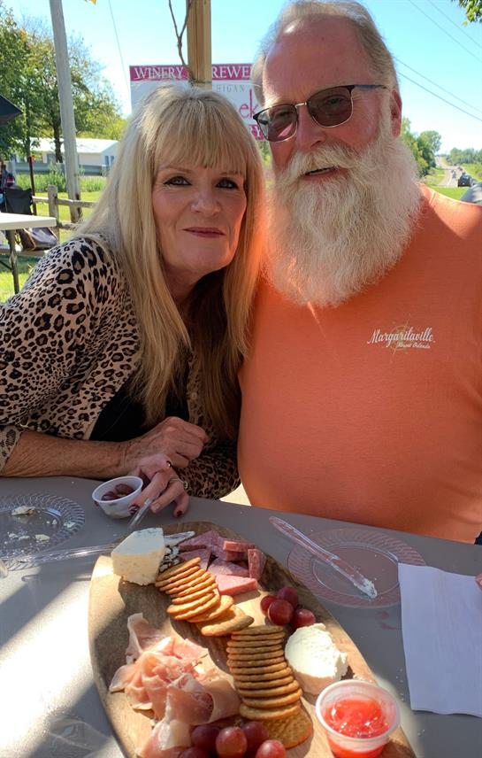 A couple smiles together while sharing tasty treats at a festive outdoor gathering.