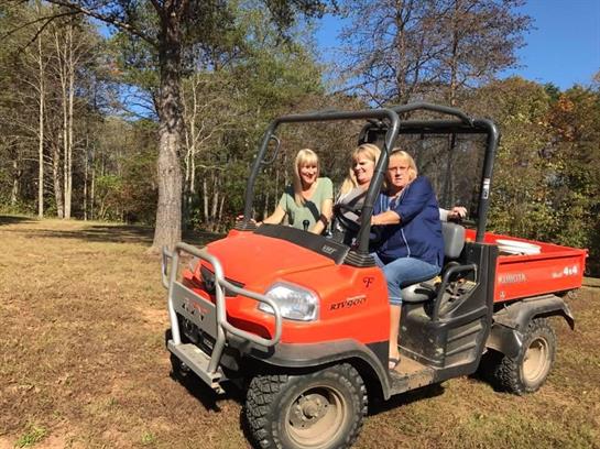 Three friends have fun driving an all-terrain vehicle on a sunny day in the countryside.