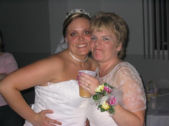 Two women pose happily at a wedding reception, celebrating love and friendship together.