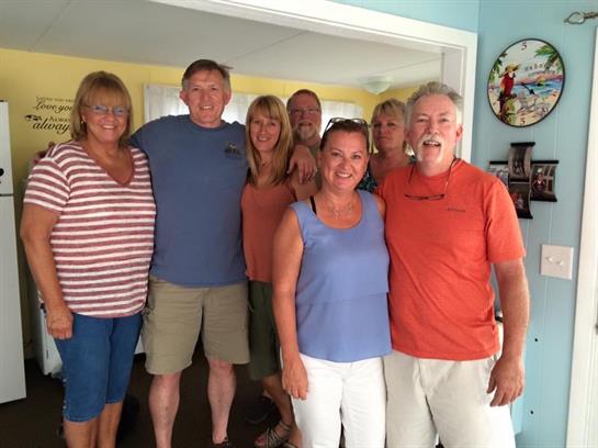 Group of friends smiles and poses together in a bright living room filled with joy.