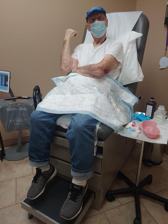 Older adult in medical chair waiting for treatment, wearing a mask and hospital gown