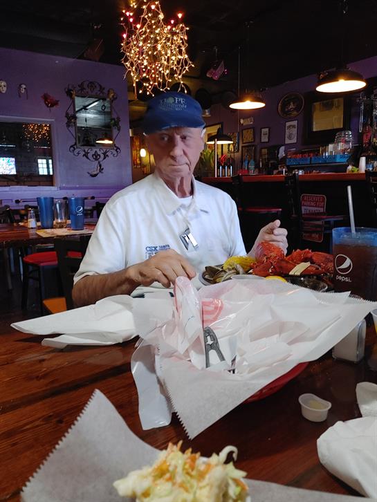 A retired man sits at a wooden table in a colorful diner, savoring a hearty meal with attention.