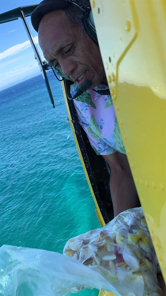 A person enjoys a helicopter ride, taking in the stunning ocean views and coastline ahead.