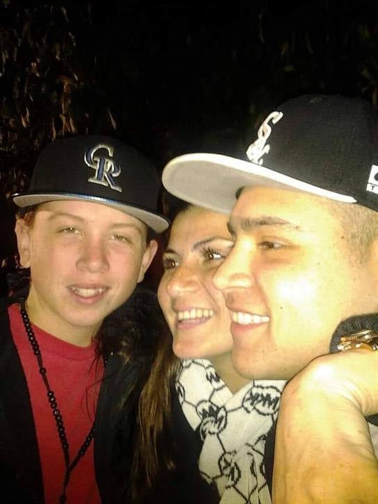 A joyful gathering of three friends smiling and posing together in a lively atmosphere at night.