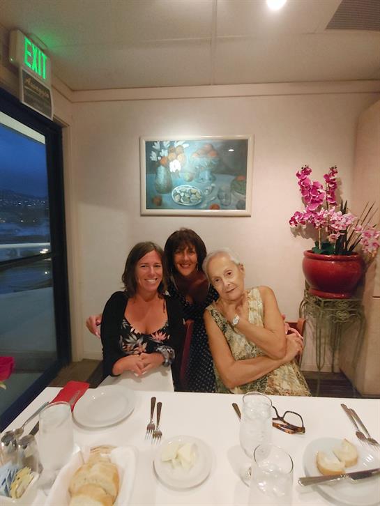 Three women sit at a table in a restaurant, sharing smiles and conversation while dining.
