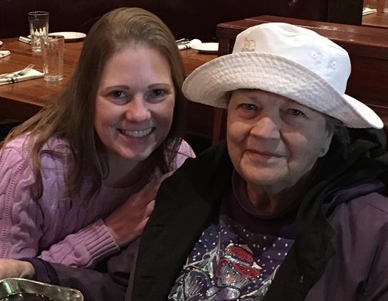 Two women share smiles while posed together at a table in a cozy restaurant setting.