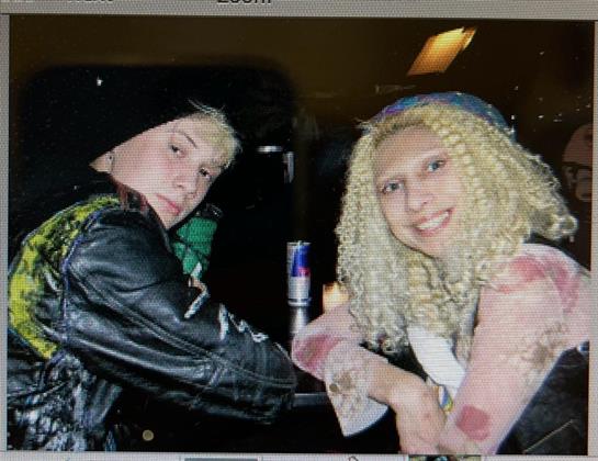 Two friends share laughter while posing at a lively venue during an energetic night out.