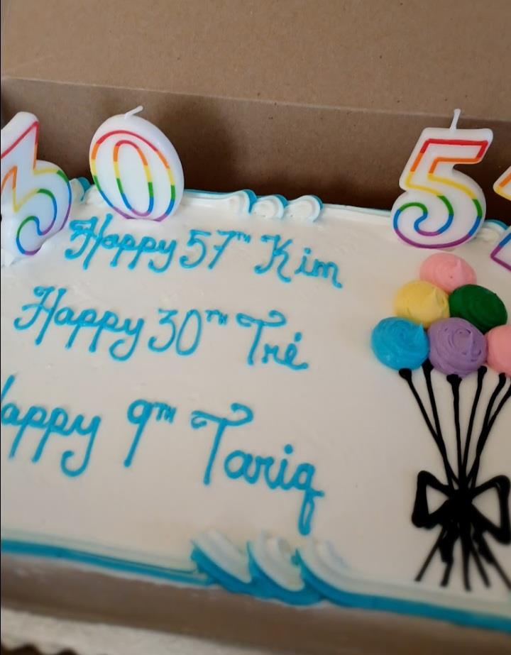 A decorated cake wishes happy birthday to four, adorned with candles and pastel colors.