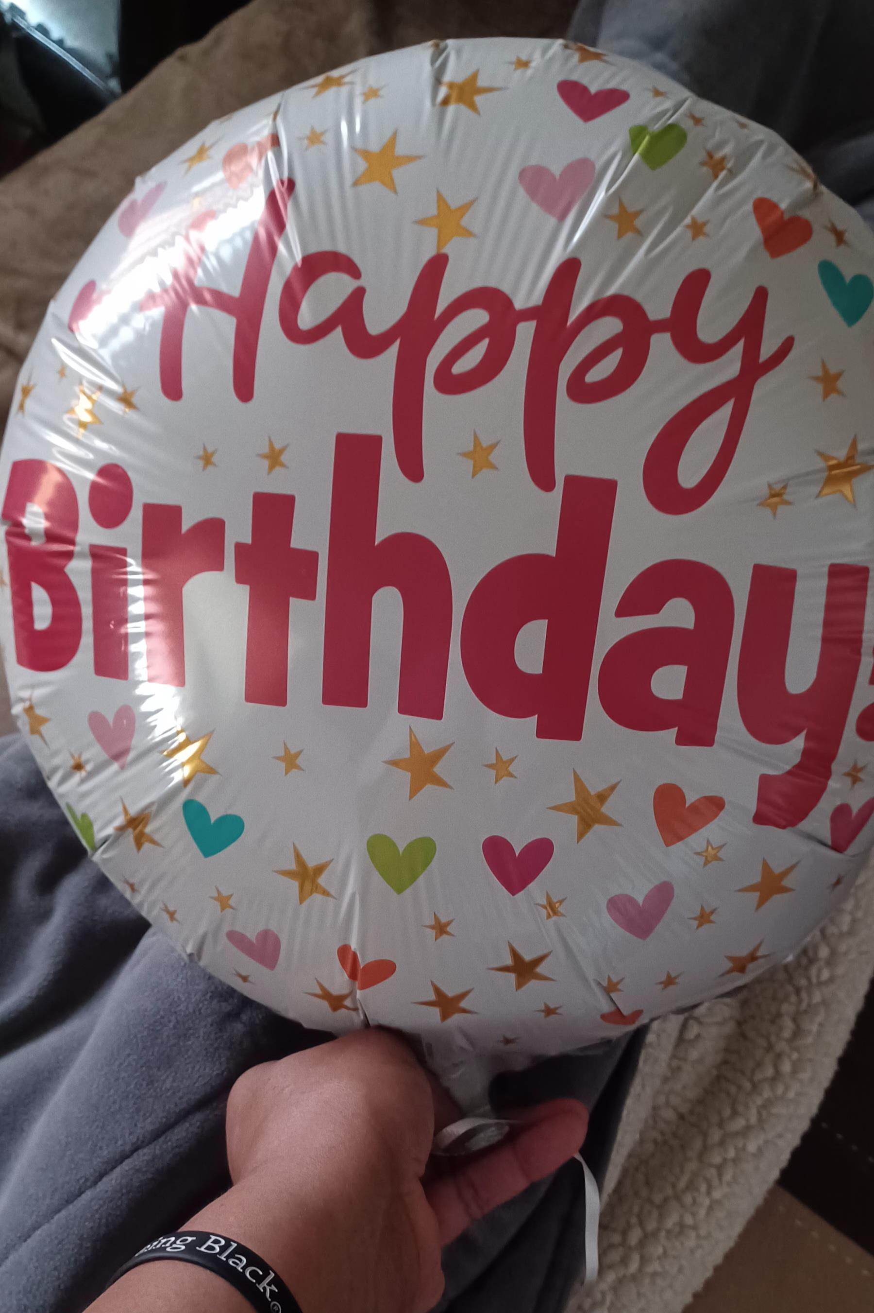 A vibrant balloon with a birthday message is held in a hand, symbolizing festive celebration.