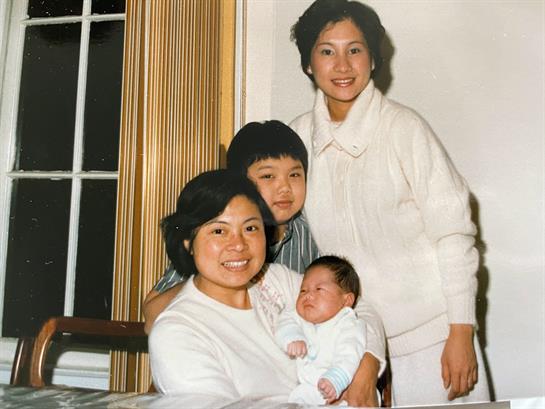A warm family moment featuring a mother holding a baby, with grandmother and child nearby.