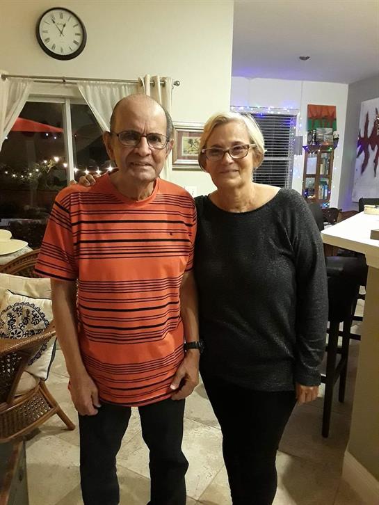 Two people stand close together, smiling in a well-decorated living room with inviting atmosphere.