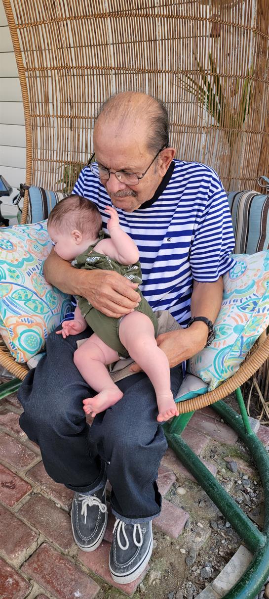 A joyful grandfather holds his grandchild close on a comfortable chair outside.