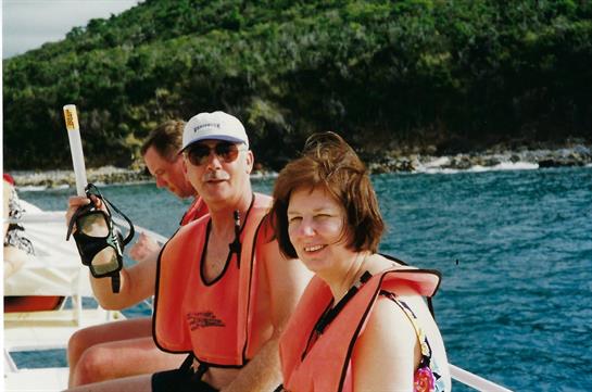 Excited people enjoy snorkeling together while wearing life jackets in clear blue water.
