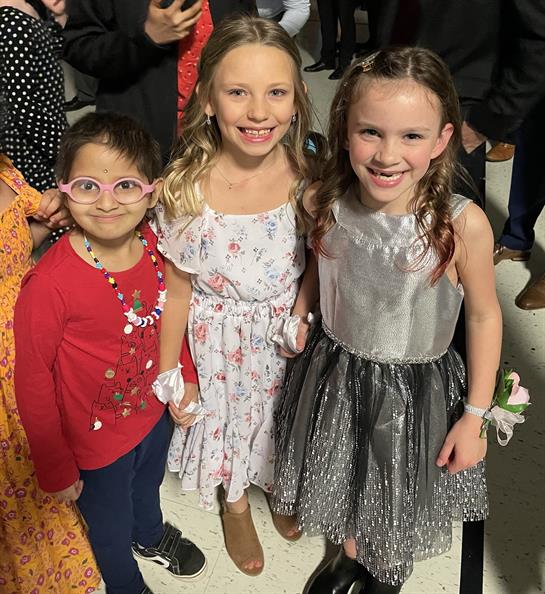 Children dressed in colorful outfits gather and laugh at a joyous celebration in the sunlit space.