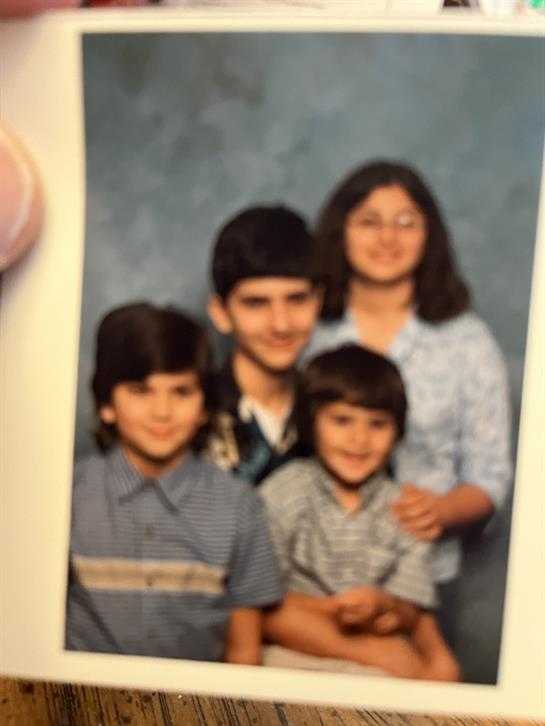 Siblings stand closely together, smiling and displaying a sense of unity in a friendly manner.