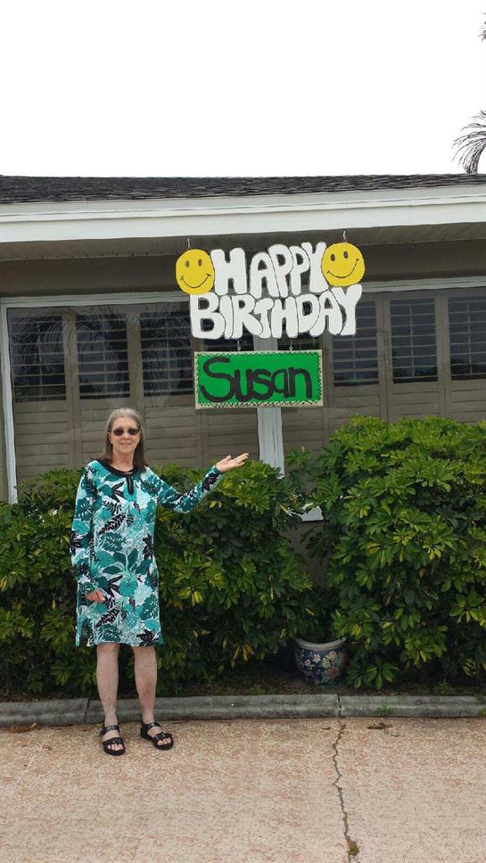 Susan stands outside her home, proudly showcasing birthday decorations in vibrant colors.