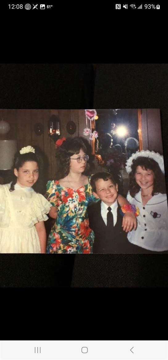 Four children are posing together in colorful outfits at a joyful gathering.