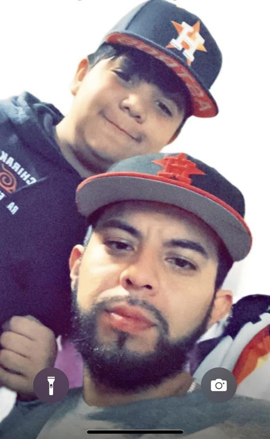 Two young men smile in matching hats at a casual home gathering.