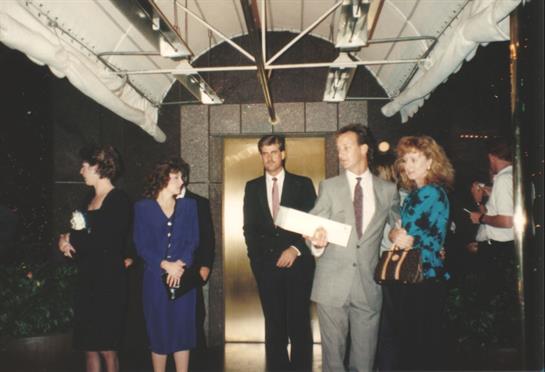 Well-dressed people chat in a stylish hallway, eager for an upcoming event.