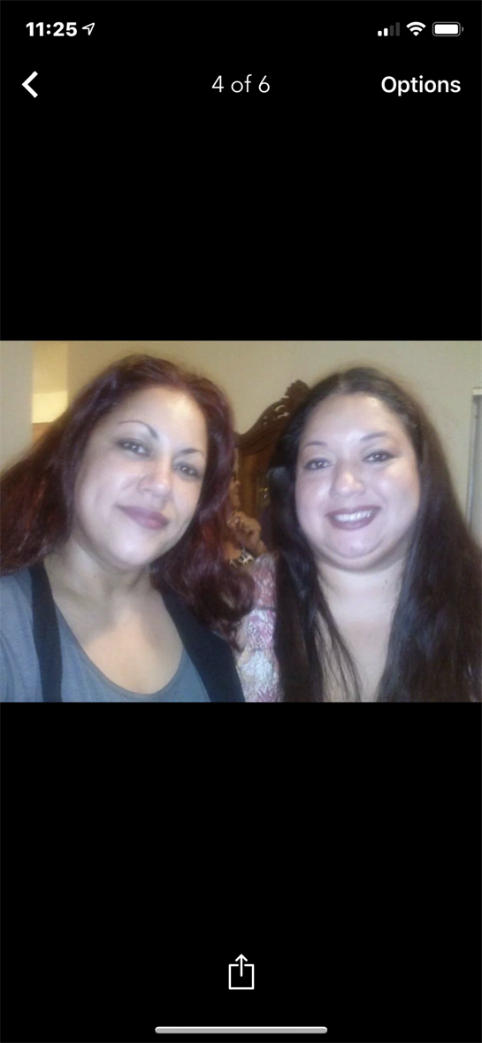 Two friends pose happily for a picture in a warm, inviting room filled with social energy.