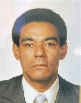 A man wearing a suit displays a serious expression, likely for official identification.