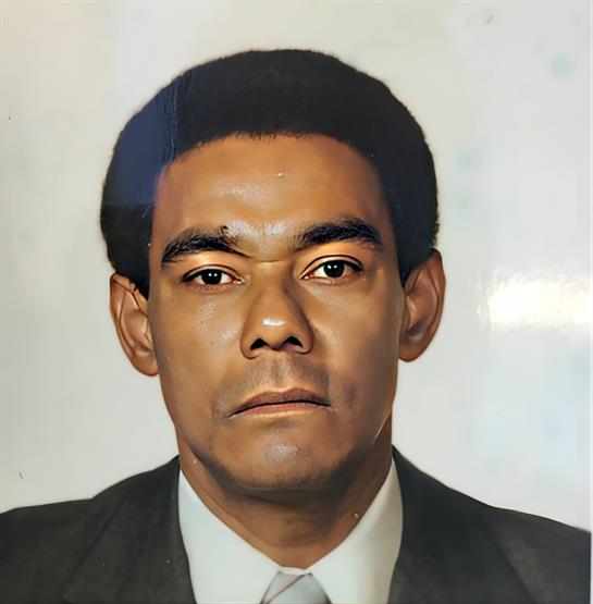 A man dressed in a suit poses for a professional portrait, exuding calm and composure.