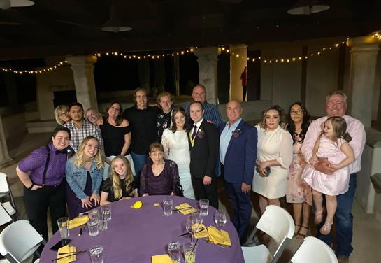 Friends and family gather around tables dressed for a joyful celebration in a warm setting.