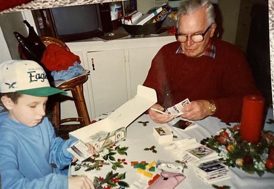 Two family members enjoy sorting baseball cards together in a cozy indoor setting.