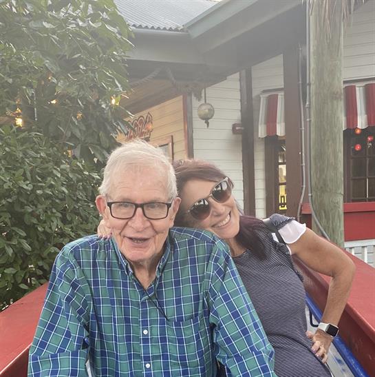 Two friends relax and smile together outside a charming cafe in warm afternoon light.
