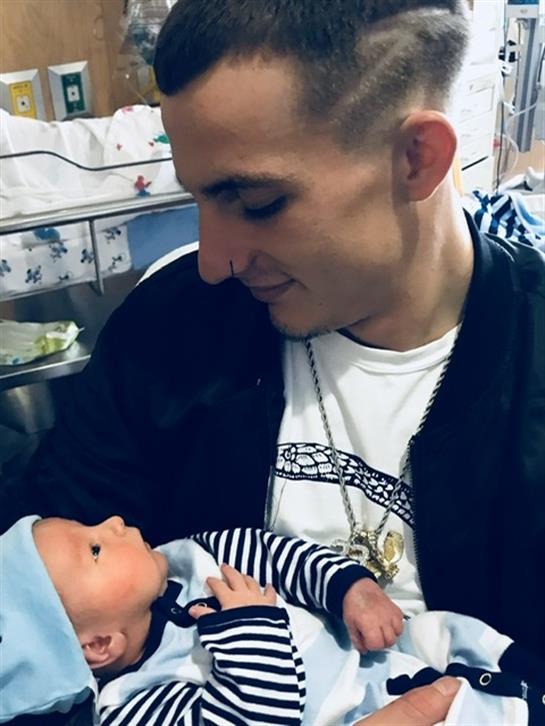 Father and infant share a loving gaze in a hospital nursery, surrounded by a warm atmosphere.