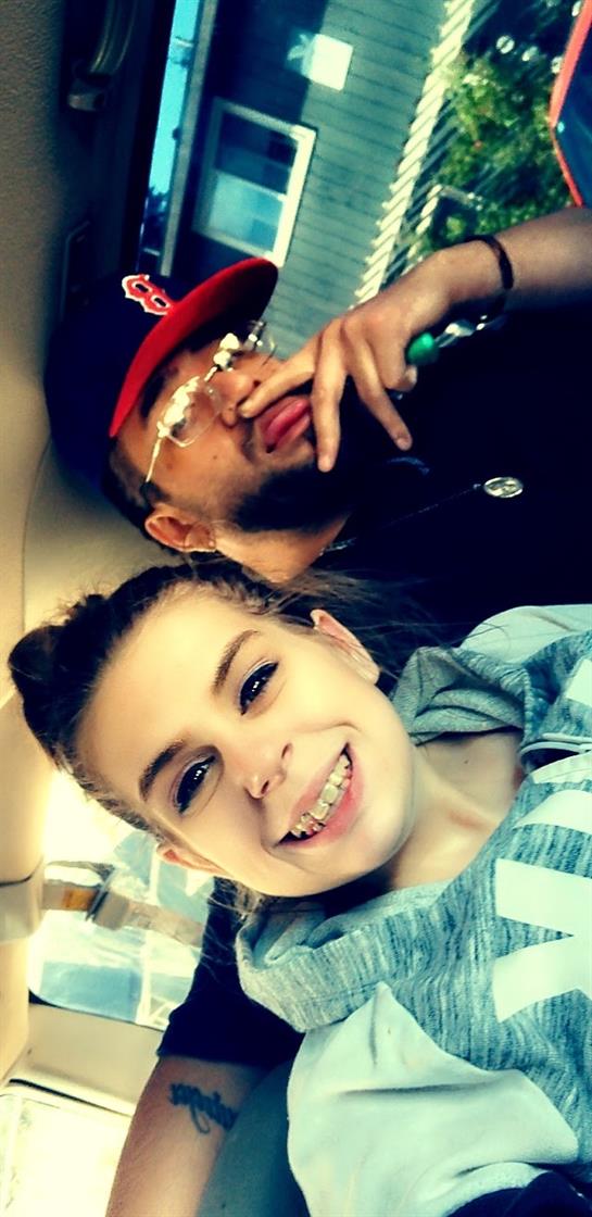 Two individuals share a cheerful moment in a vehicle, smiling and engaging with each other.