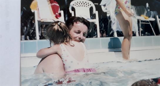 A joyful moment unfolds as a child hugs an adult in a pool, showcasing family love and fun.