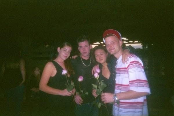 Four friends pose with roses, laughing and enjoying a festive atmosphere together.