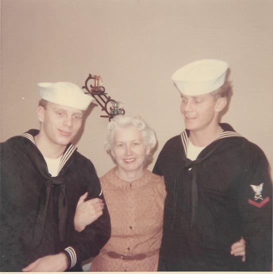 Two sailors in navy uniforms pose and smile with an elderly woman, enjoying the moment.