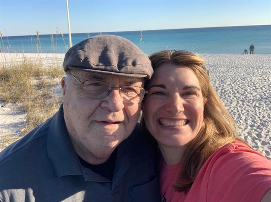 A joyful moment captures a smiling man and woman enjoying a sunny beach day together.