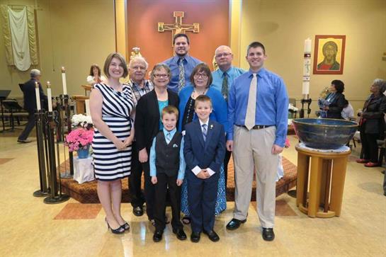 A family stands together in formal clothes, celebrating a special occasion in a church setting.