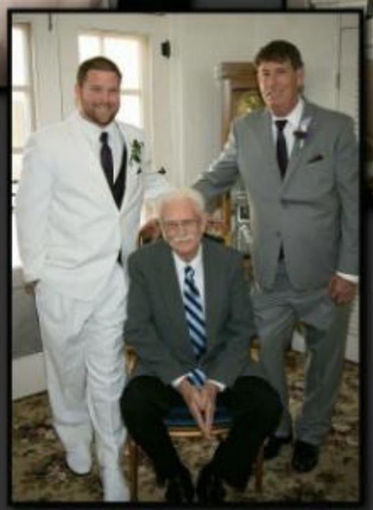 Three men in formal suits pose together, highlighting their family connection in a warm environment.