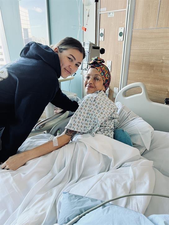 A friend smiles while visiting a hospitalized patient, highlighting friendship during recovery.