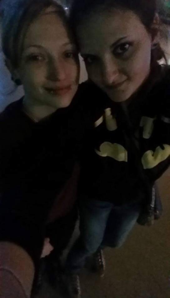 Two friends pose closely together with cheerful expressions in a relaxed indoor environment.