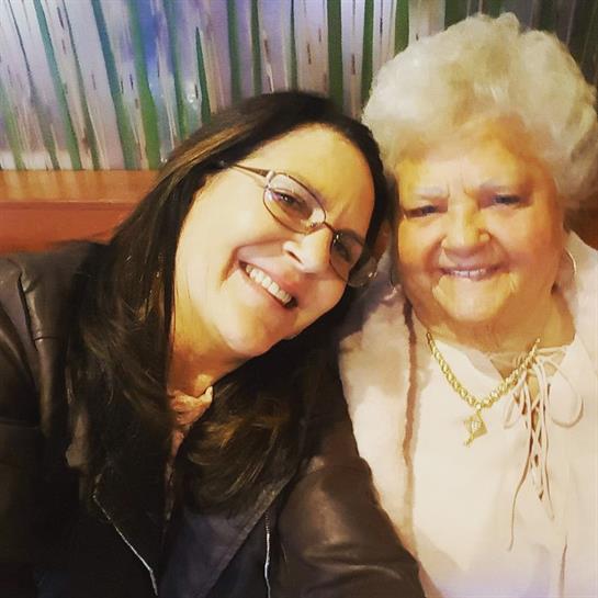 Two women share a joyful moment, smiling for a close-up picture in a warm restaurant setting.