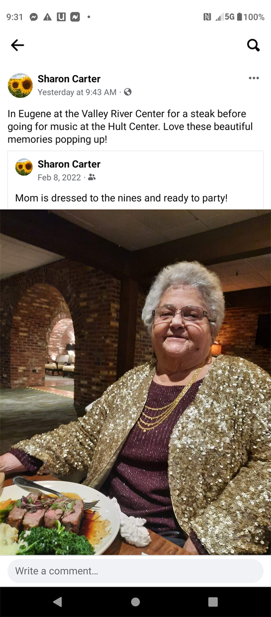 A confident woman dressed in a sparkling outfit sits at a table ready to enjoy her meal.