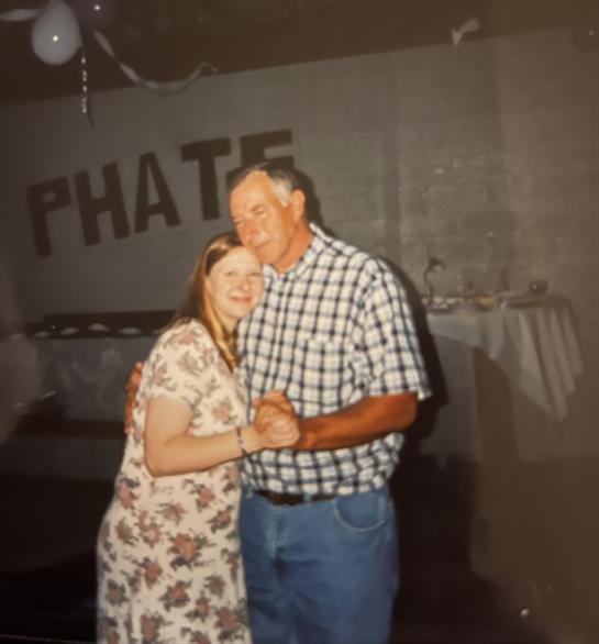 A couple enjoys a moment dancing closely together at a lively gathering in a decorated space.
