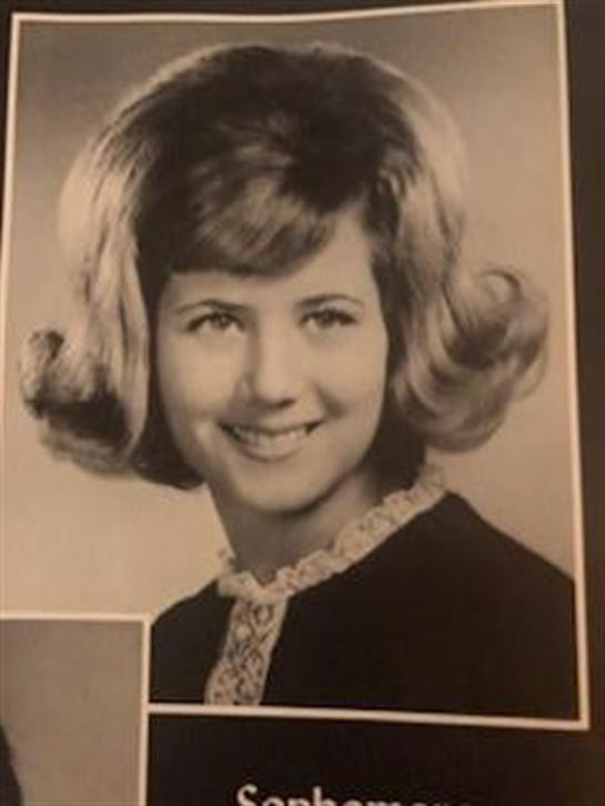 A young woman smiles in a vintage dress and hairstyle, evoking a nostalgic vibe.