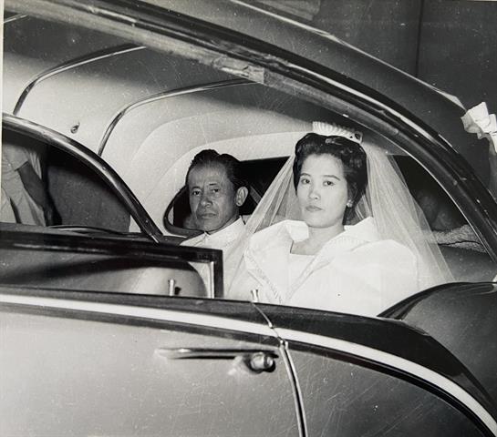 A bride and groom sit in a classic car before their wedding ceremony, sharing a moment of joy.