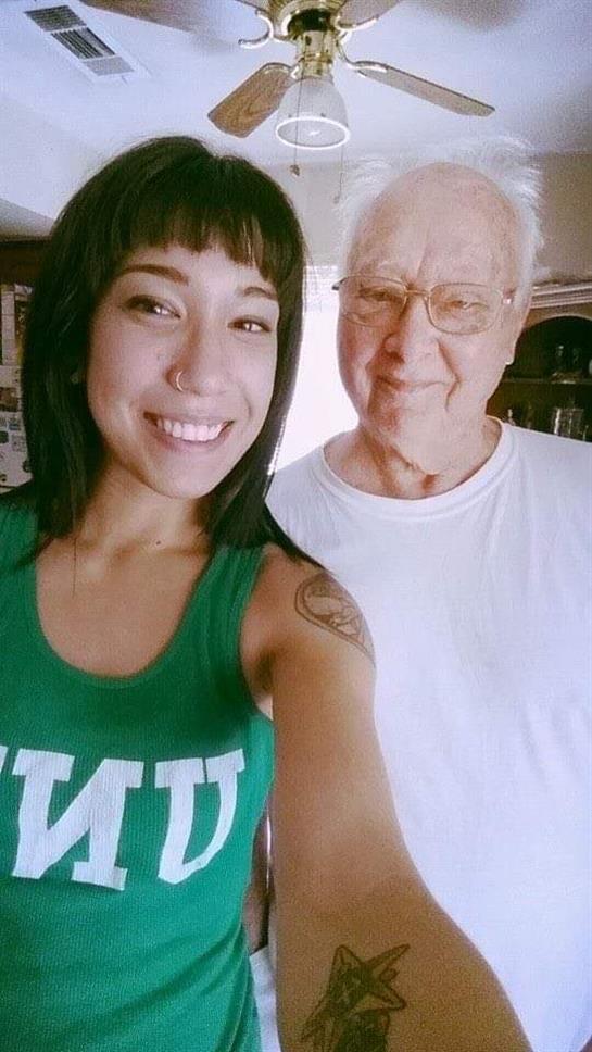 Young woman and elderly man share a joyful moment together, smiling in a cozy indoor setting.