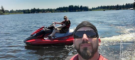 Two friends have a fun summer day riding jet skis on a sparkling lake, enjoying the outdoors.