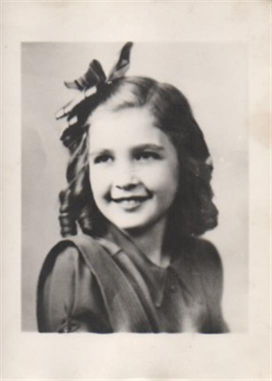 A sweet young girl in a vintage outfit with curls and a bow expresses joy in a classic portrait.