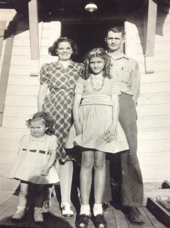 A family poses outside a quaint building, showcasing traditional attire and a nostalgic atmosphere.